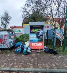 Foto: Kleidercontainer Texaid ÜBERVOLL und Deponie daneben 